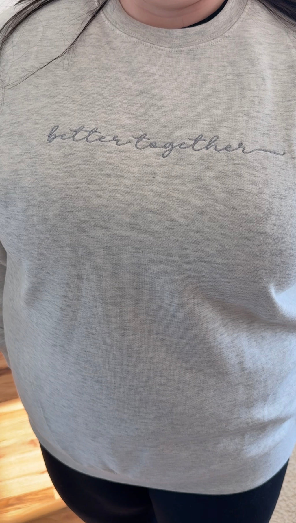 Heather oatmeal sweatshirt with 'better together' text in grey embroidery across center front worn by a person